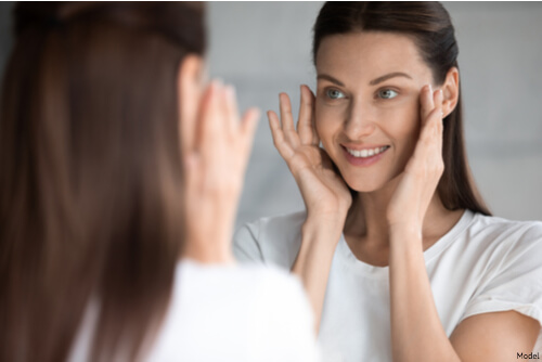 Woman putting cream on her face