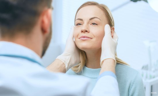 Woman receiving Halo Laser treatment in medical spa with male provider touching her face (MODEL).