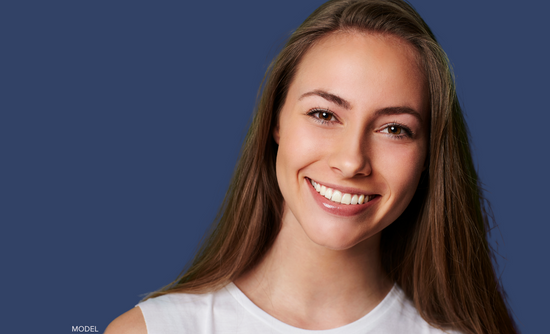 Woman smiling against blue wall (MODEL)