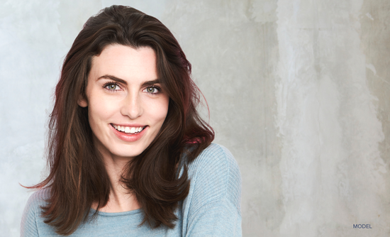 Woman wearing sweater smiling against painted wall (MODEL)