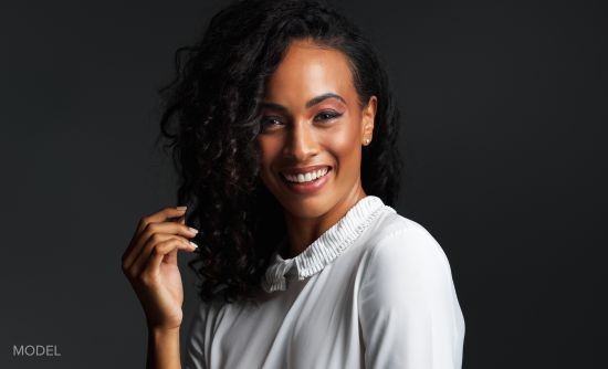Woman wearing white blouse, touching hand to her hair (MODEL)