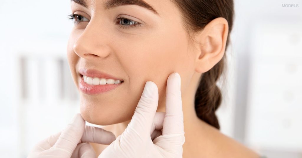 Woman having her face examined by a doctor wearing gloves (models)